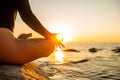 Close up hand of a woman meditating in a yoga lotus pose on the beach at sunset. Girl sitting on a warm rock with sun Royalty Free Stock Photo