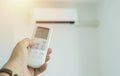 Close up hand of woman is turning on air conditioner. Air conditioner with remote controller Royalty Free Stock Photo