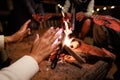 Close-up on hand of woman warming on campfire. Group of asian friends sitting around campfire in the night.