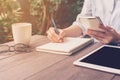 Close up hand woman writing notebook in coffee shop with vintage Royalty Free Stock Photo