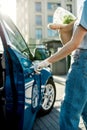 Close up of hand of woman in protective glove opening the blue car door while holding grocery bag, Protective measures Royalty Free Stock Photo