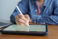 Close up hand working woman work and writing on tablet. On wooden desk background have laptop