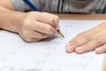 Close up hand writing homework on wooden table at home. Kid learing and writing alphabet Royalty Free Stock Photo