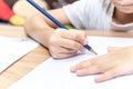 Close up hand writing homework on wooden table at home. Kid learing and writing alphabet