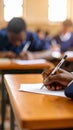 Close-up of a hand writing with a pen on paper during an exam in a classroom. Royalty Free Stock Photo