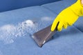 Close-up of a hand in yellow gloves cleaning the blue sofa cloth using a washing vacuum cleaner Royalty Free Stock Photo