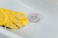 Close-up of a hand in a yellow rubber glove wipes a white sink with a sponge. Royalty Free Stock Photo