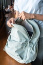 Close-up of the hand of a young female student packing a blue backpack with belongings to college or university