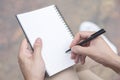 Close up hand young man are using pen writing Record Lecture note pad into the book sitting on the chair outdoor. Royalty Free Stock Photo