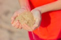 Close-up of a handful of sand in the hands of a young woman