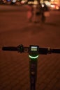 Close-up of the handle of an electric scooter at night with the digital display of the battery charge
