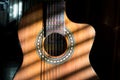 Close up of handmade classical guitar with striped shadows across the body and neck