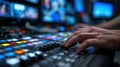 Close-up of hands adjusting a control panel in a bustling television studio, with blurred monitors and newsroom activity Royalty Free Stock Photo