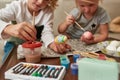 Close up of hands of adorable little boy painting colorful Easter eggs together wih his sister while spending time at Royalty Free Stock Photo