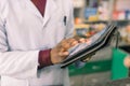 Close-up of hands of African American man doctor or pharmacist using digital tablet while standing in interior of