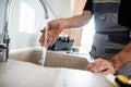 Close up of hands of aged repairman in uniform working, checking water stream, fixing broken kitchen tap. Repair service Royalty Free Stock Photo