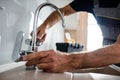 Close up of hands of aged repairman in uniform working, fixing broken kitchen tap using adjustable wrench. Repair Royalty Free Stock Photo