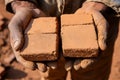 A close-up of hands arranging dusty clay bricks, highlighting manual labor, traditional building methods, and Royalty Free Stock Photo