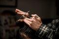 close-up of hands of barber holding strand of hair and scissors and do haircut Royalty Free Stock Photo