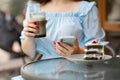 Close up of hands beautiful woman reading news on her smartphone eating cake at outdoors cafe Royalty Free Stock Photo