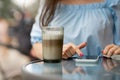 Close up of hands beautiful woman reading news on her smartphone eating cake at outdoors cafe. Royalty Free Stock Photo