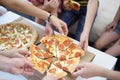 Hands of big company take piece of round shaped pizza