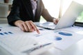 Close up hands of business woman pointing at financial chart paper and using laptop in office Royalty Free Stock Photo