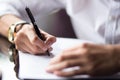 Close up of the hands of a businessman in a shirt signing or writing a document on a sheet of white paper using a nibbed Royalty Free Stock Photo