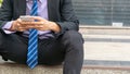 Close up hands businessman uses smartphone sitting at walkway pedestrian