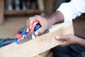 Close up hands of Carpenter busy working by using block plane for removing rough surfaces on wood at shop - concept of