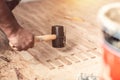 Close up hands of Carpenter on work laying laminate or parquet flooring use a rubber mallet, Worker installing wooden laminate