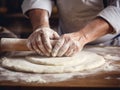 close-up of the hands of a chef who is rolling out the dough with a rolling pin