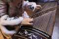 Close up of hands of a Chinese woman playing a zither, a traditional Chinese musical instrument