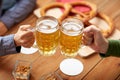 Close up of hands clinking beer mugs at bar or pub Royalty Free Stock Photo