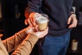 Close up of hands with coffee. Barman giving a freshly brewed fragrant cappuccino with high milk froth in a transparent glass to