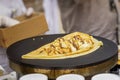 Close-up of hands of cook in gloves preparing Crepe, pancake on frying pan with fresh banana, sweet sauce, nutella