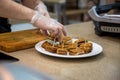 close up of hands of a cook man in rubber gloves put on a white plate snacks grilled sandwiches. close up, soft focus, background