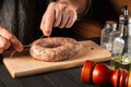 Close-up hands of a cook tying a thread of homemade sausage. Cooking sausages with meat and spices on a cutting board