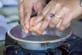 hands cracking egg into a pan