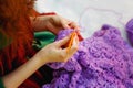 Close-up of hands crocheting. A woman with red hair knits lilac clothes. Selective focus Royalty Free Stock Photo