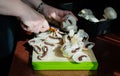 Close-up of hands are cutting fresh mushrooms on a cutting board. Homemade vegetarian cuisine. Sunlight from window, shadows on Royalty Free Stock Photo