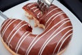 Close up hands cutting a piece of chocolate donuts by knife and fork Royalty Free Stock Photo