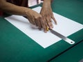 Close-up hands cutting white paper with cutter and iron ruler on green mat Royalty Free Stock Photo