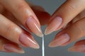 Close up of hands doing a french manicure on a white background, closeup view of a woman hand with a nail file and Royalty Free Stock Photo