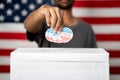 Close up of Hands dropping multiple I Voted sticker inside Ballot box with US flag as background, Concept of fraud in