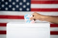 Close up of Hands dropping multiple I Voted sticker inside Ballot box with US flag as background, Concept of fraud in