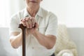 Close-up of hands of an elderly man holding onto a cane