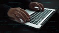 Professional hands typing on a sleek laptop keyboard in a dark environment with overlay of coding symbols and binary Royalty Free Stock Photo