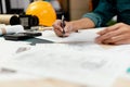 Close up hands of an engineer working and checking on blueprints. Engineer planning project on paperwork with equipment Royalty Free Stock Photo