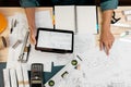 Close up hands of an engineer working and checking on blueprints with tablet. Engineer planning project on paperwork with equipmen Royalty Free Stock Photo